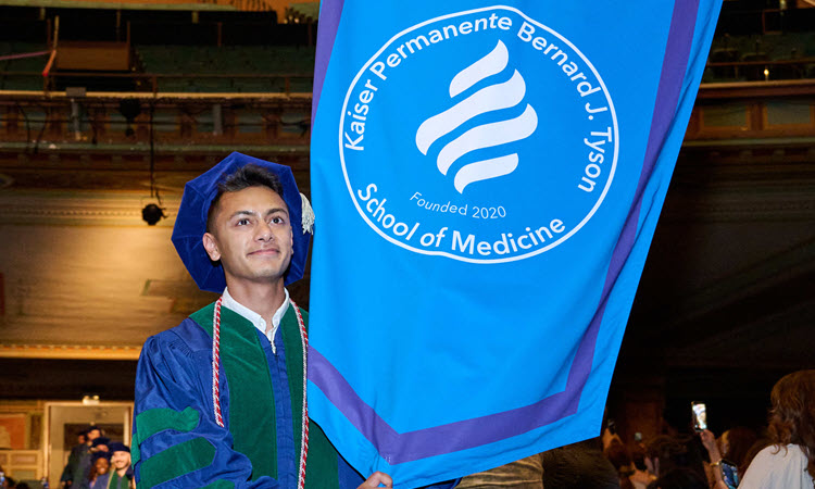 Class 0f 2026 student carrying KPSOM banner.
