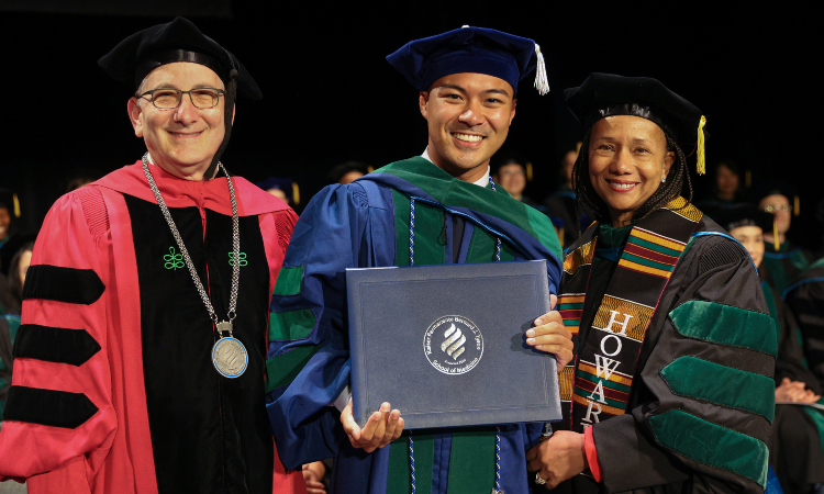 student holding diploma with dean and faculty member