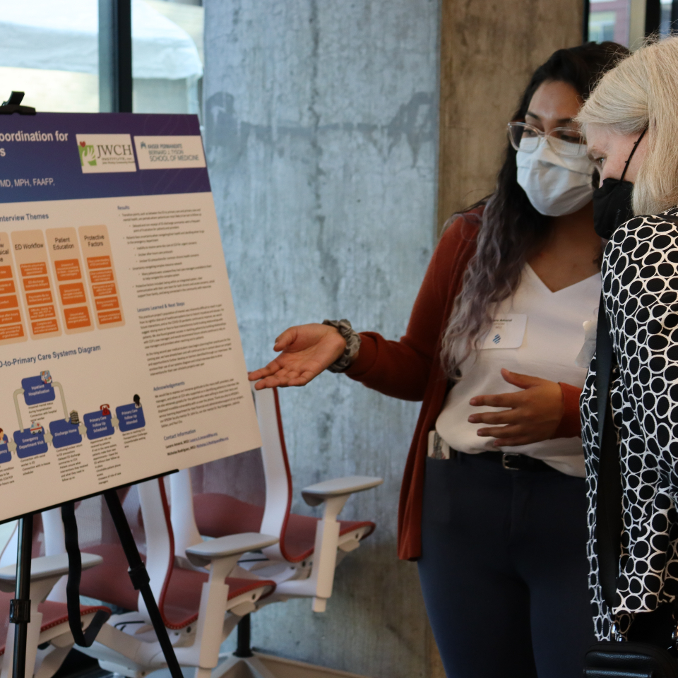 A KSPOM student discusses their project with a faculty member during the 2023 Service-Learning Practicum celebration event.