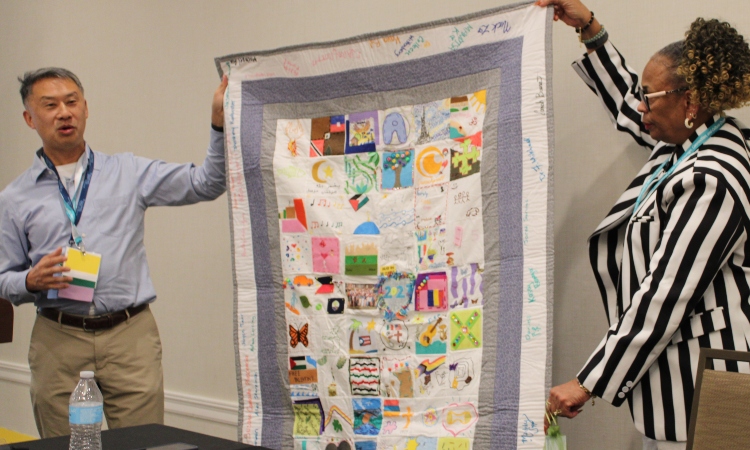 Dr. Roland Tang (left) shares a class quilt representing student identities.