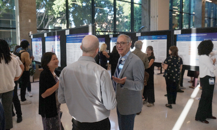 KPSOM Dean and CEO John L. Dalrymple, MD, chats with attendees as faculty, students, and visitors peruse the student research projects on display at the symposium.