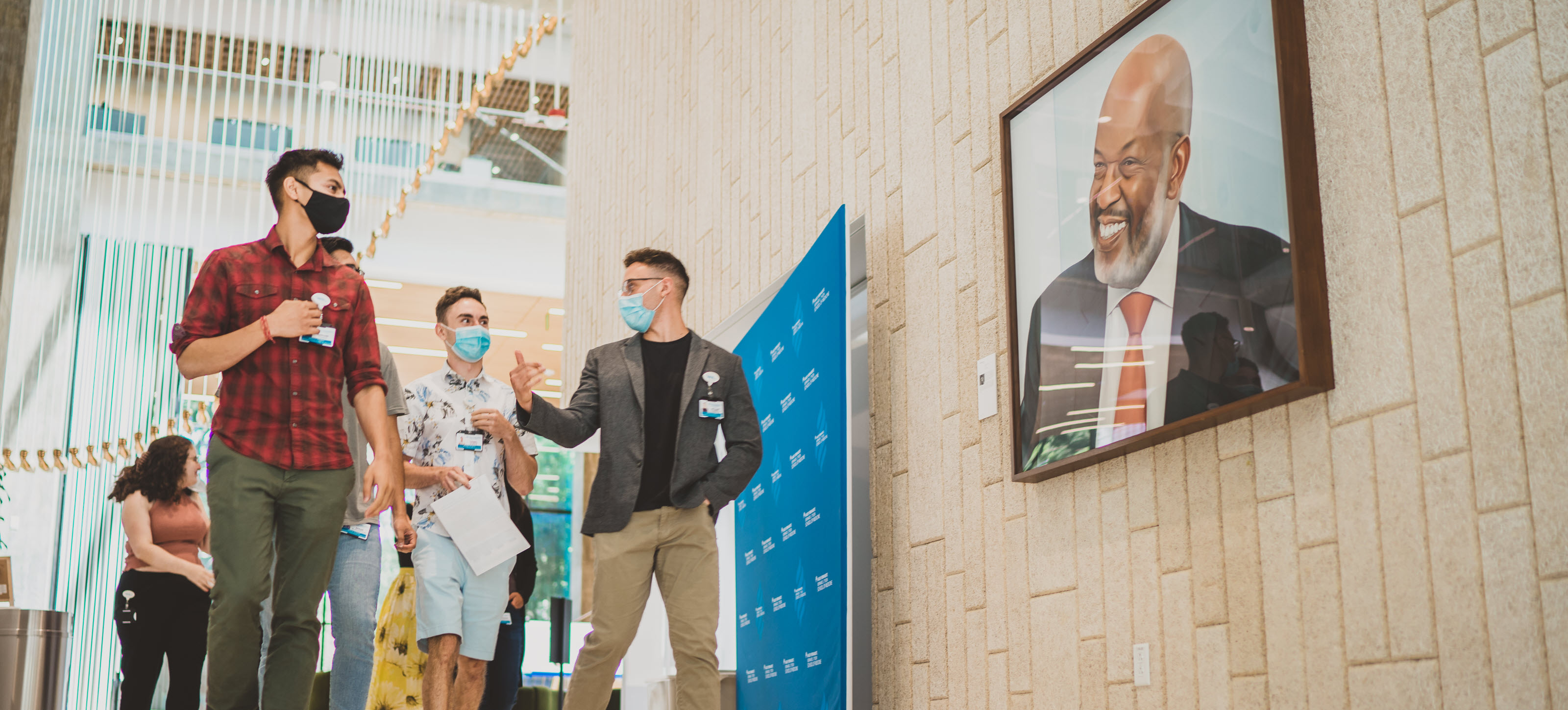 Medical students walk past the portrait of Bernard J. Tyson on the KPSOM campus.